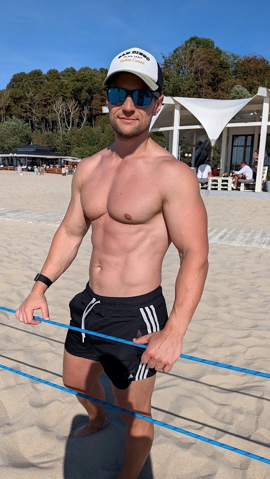 Gleb standing on a beach in sunglasses and shorts